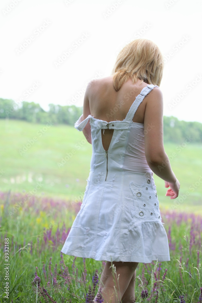 Girl in white dress going away on meadow Girl in white dress going away on meadow
