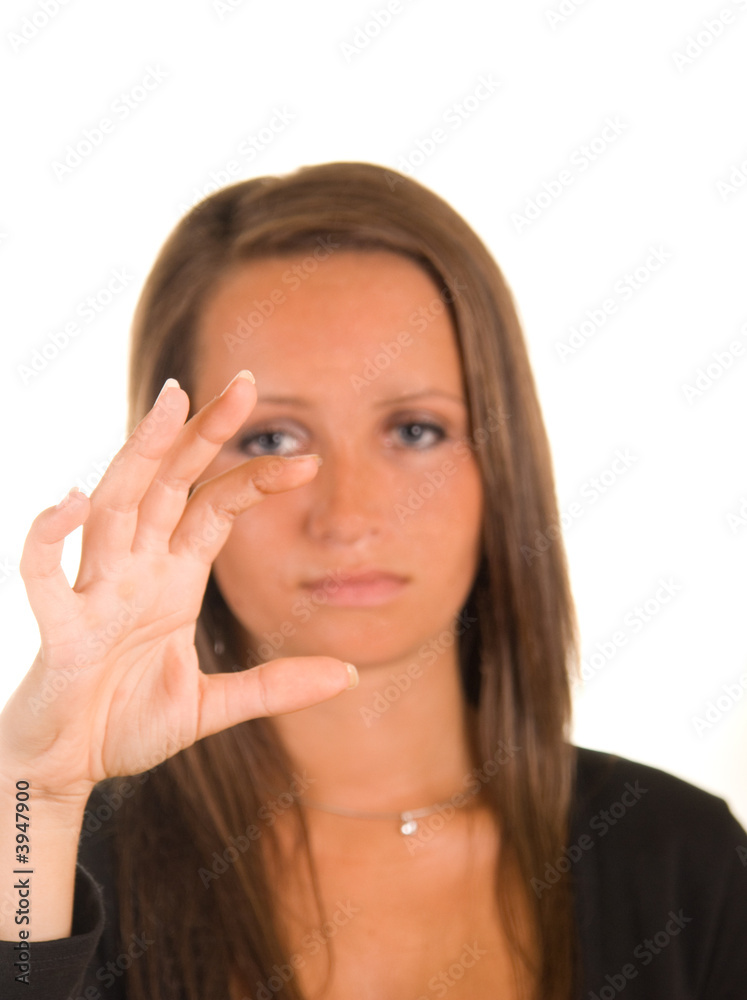 young woman looking at an invisible object in her fingers young woman looking at an invisible object in her fingers