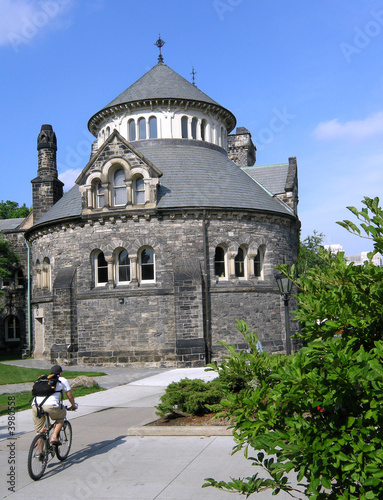 Photography Cyclist rides past round gothic building on college campus
