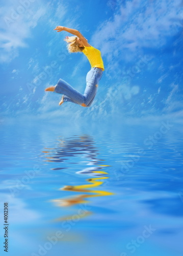 Beautiful blonde girl jumps over water
