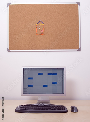 Office computer, keyboard and mouse. Cork board and pin house.
