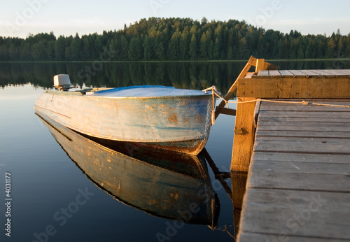 boat reflecting in calm waters of forest lake