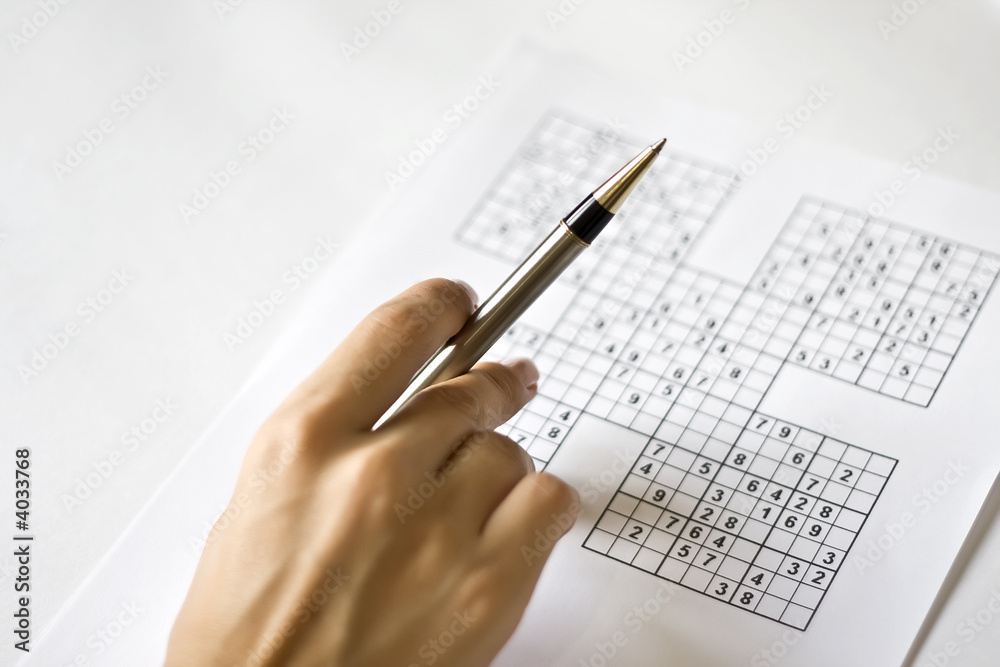 A hand on sudoku grid A hand on sudoku grid
