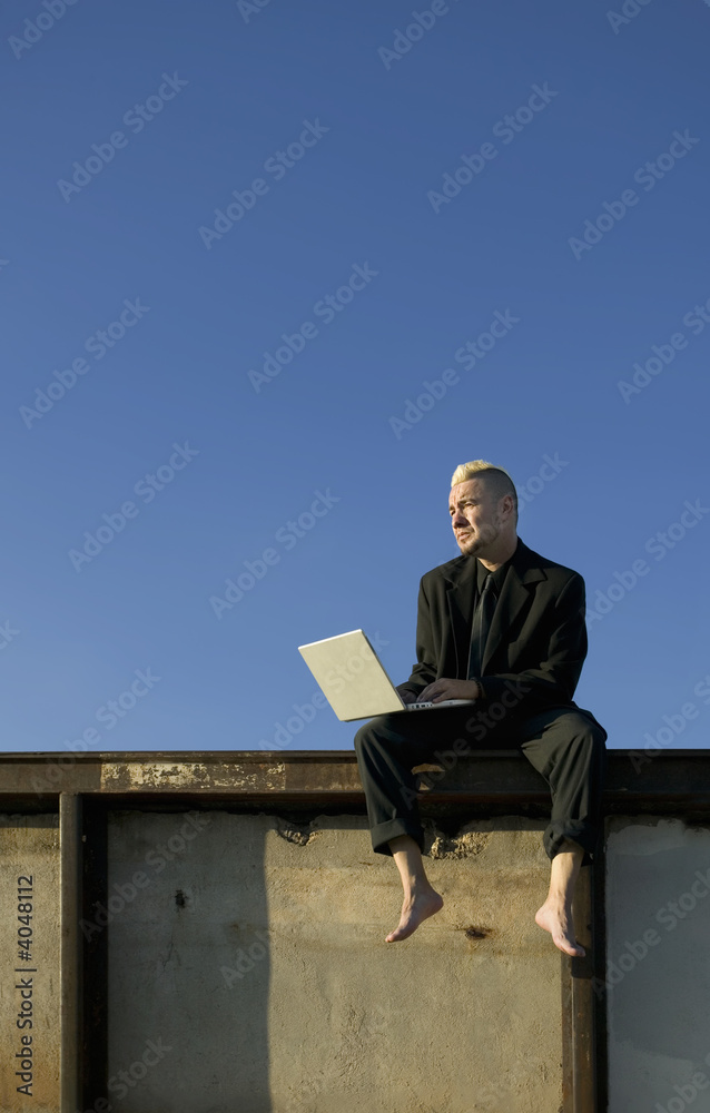 Barefoot Punk Businessman on a Wall with Laptop Computer Barefoot Punk Businessman on a Wall with Laptop Computer
