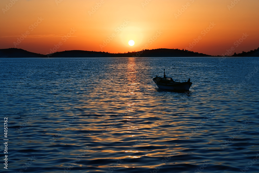 Magnificent sunset and anchored boat at sea