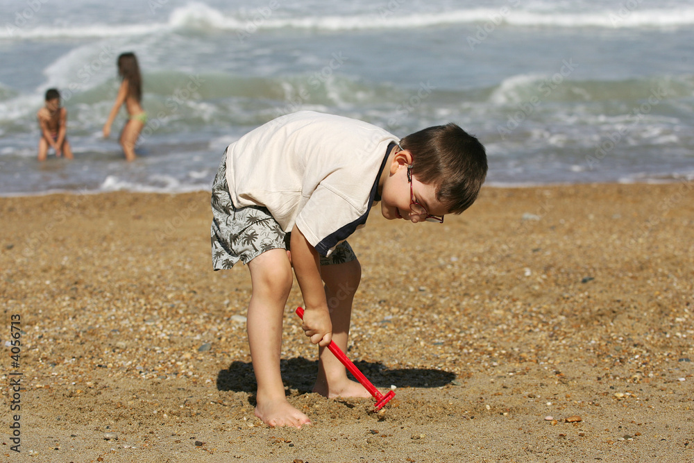 petit garçcon qui joue avec un rateau sur la plage petit garçcon qui joue avec un rateau sur la plage