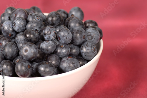 Blueberries in a bowl with a wine colored background