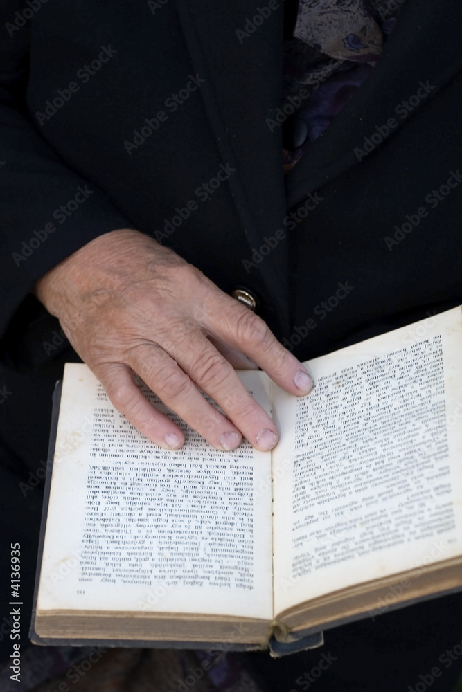 Senior's hands on old book Senior's hands on old book