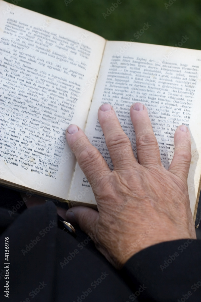 Naklejka premium Senior's hands on old book