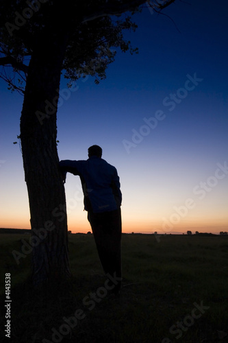 A man's silhouette in the sunset with a tree