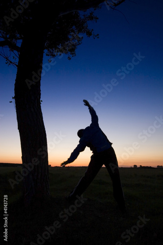 A man s silhouette in the sunset with a tree