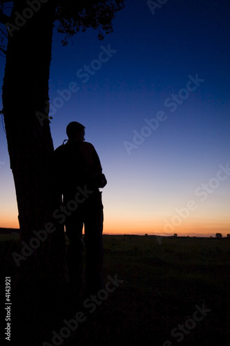 A man's silhouette in the sunset with a tree © Kavita
