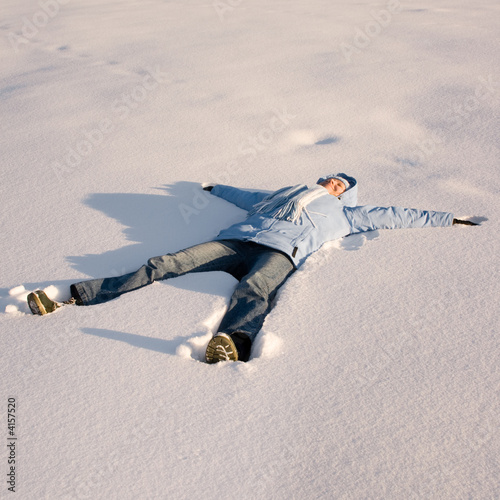 Happy young girl lying in the snow