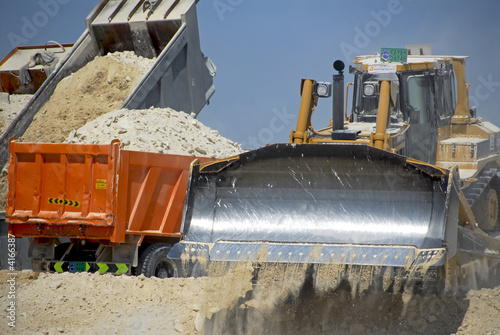 Tractor Pushing Earth & Trucks With Payloads