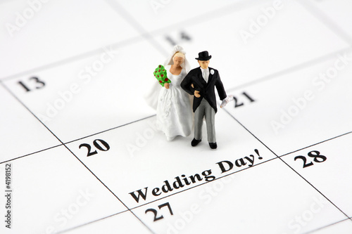 Miniature bride and groom on a calendar that says Wedding Day