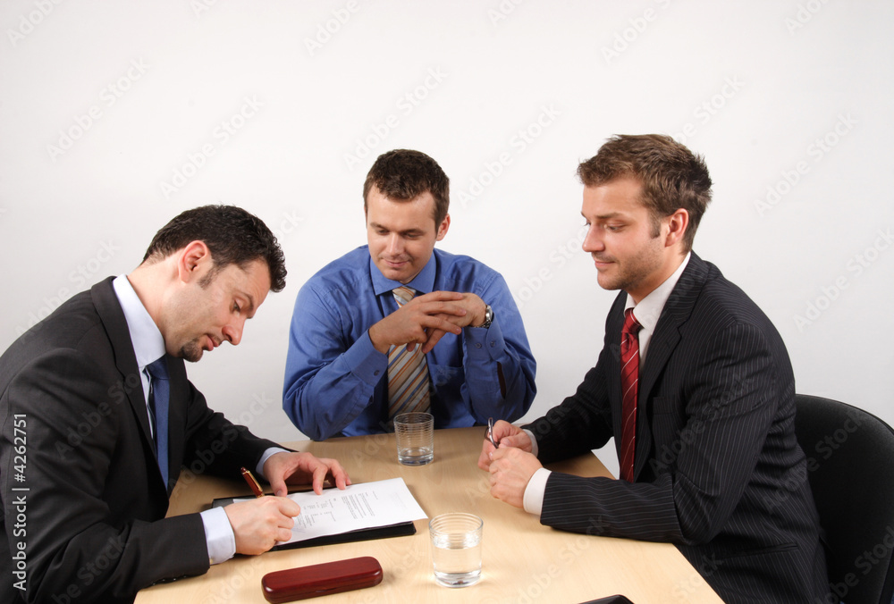 Businesspeople negotiating and signing a contract. Businesspeople negotiating and signing a contract.