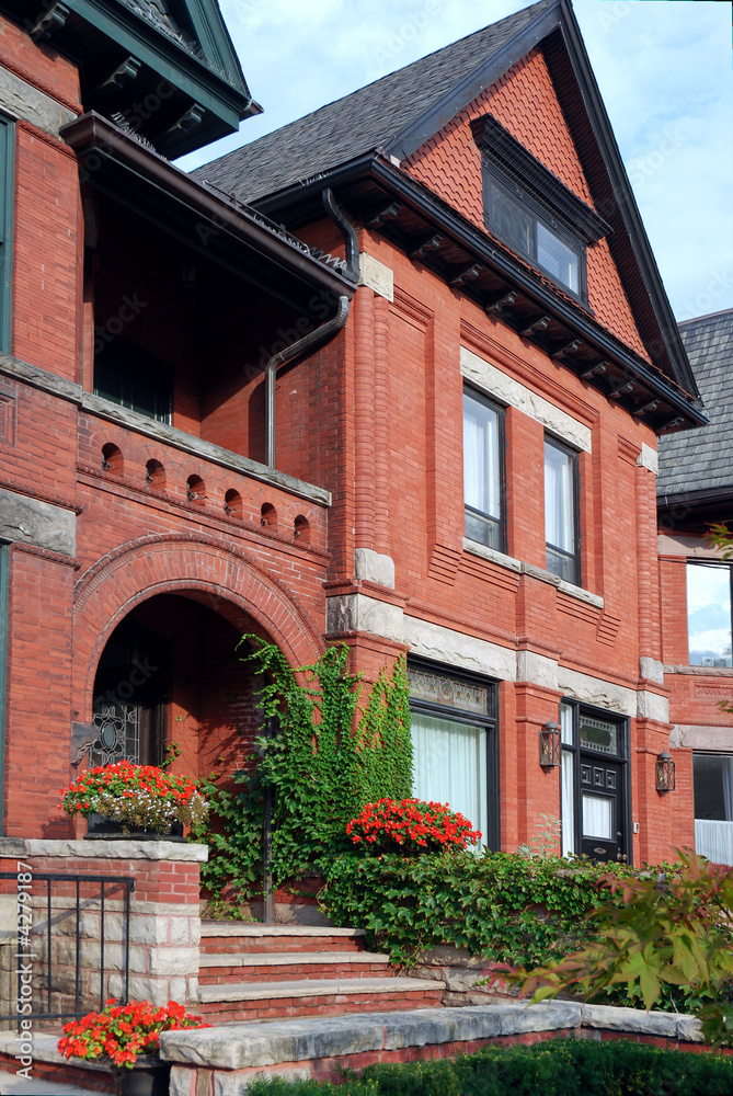 Naklejka premium Victorian red brick house with ivy and arched entrance