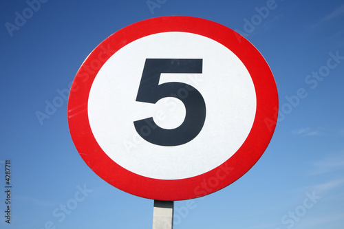 A round 5 miles per hour sign and a blue sky.