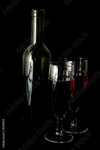 Two glasses of wine and a wine bottle on a black background 