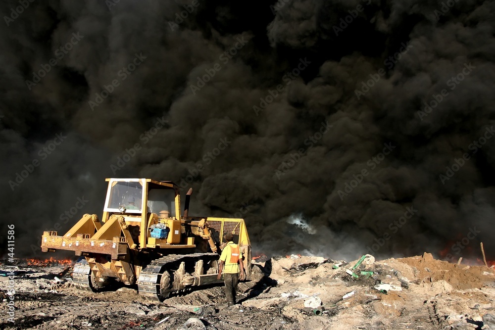 Bulldozer putting out fire of tyres at a tip site 