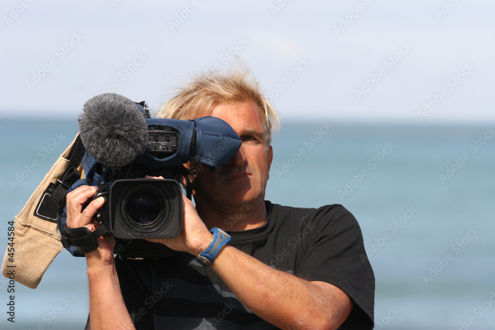 homme entrain de filmer avec une caméra professionnelle - obrazy, fototapety, plakaty 
