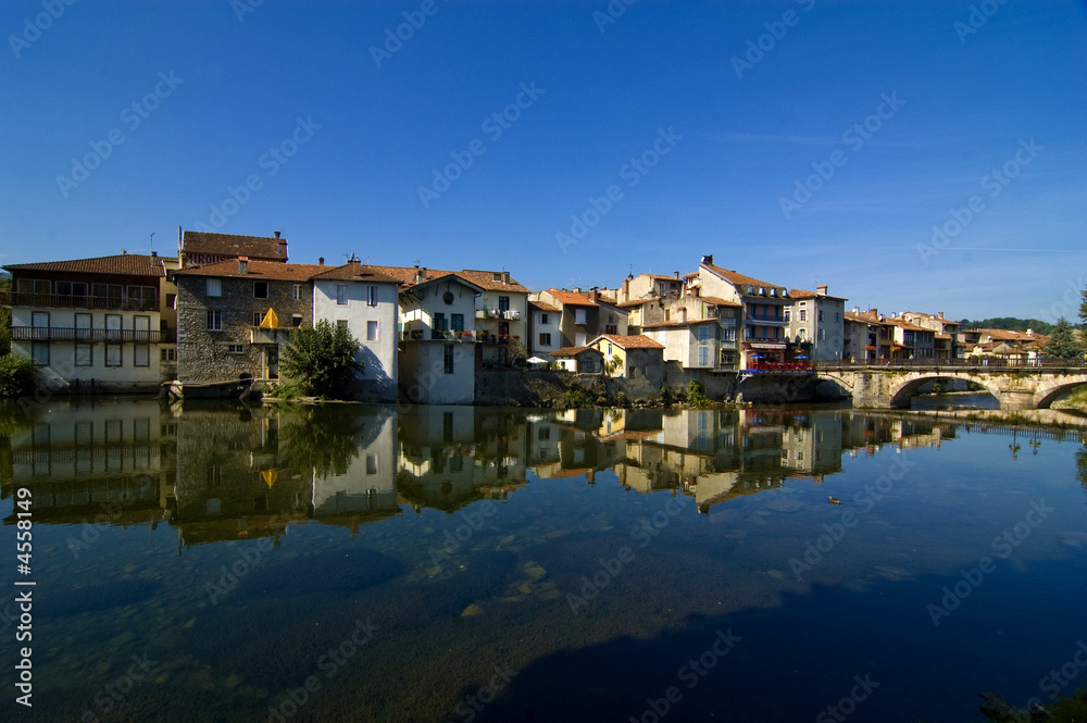 French village against blue sky and reflected in river