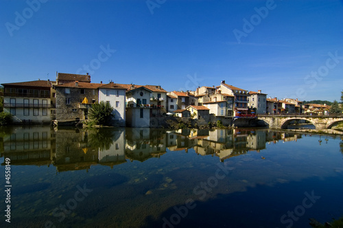 French village against blue sky and reflected in river