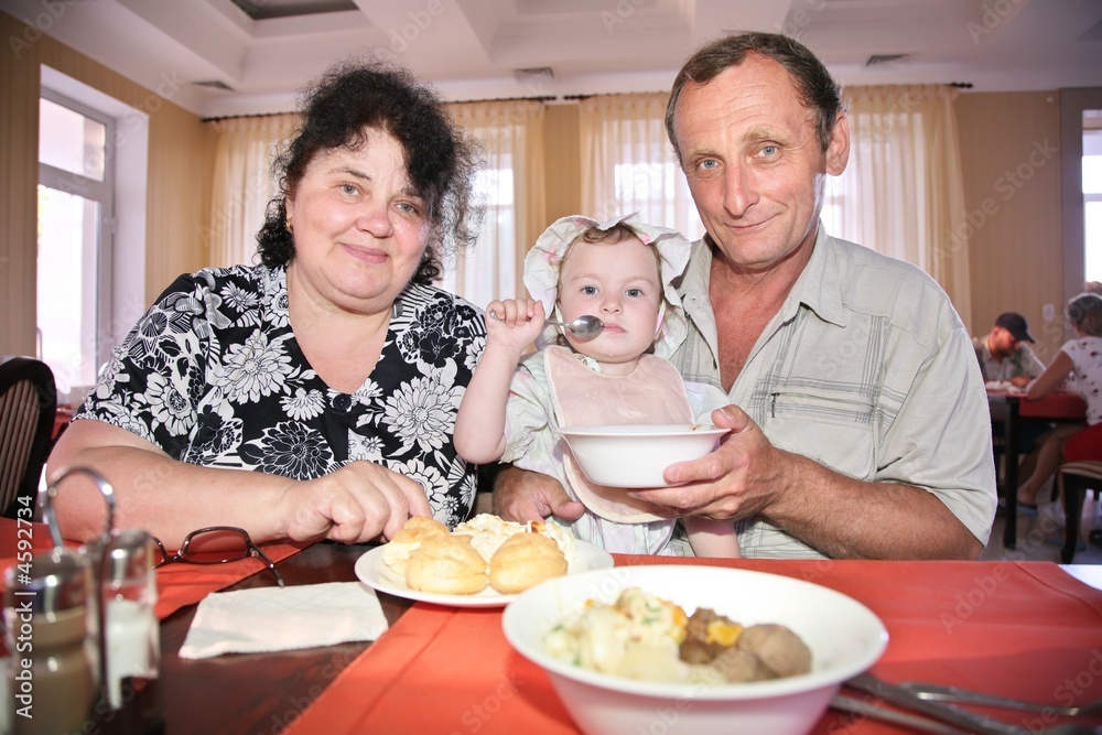 Grandmother with grandfather feeds child Grandmother with grandfather feeds child