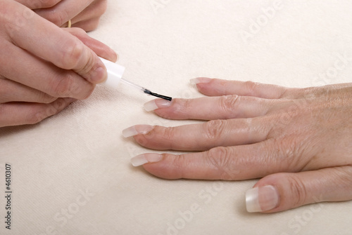 Applying clear nail varnish to acrylic finger nails