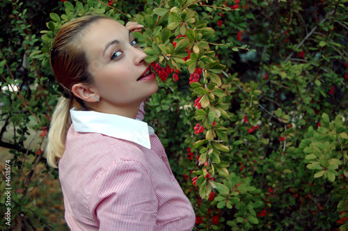 Coquetish girl trying to bite red barberries photo