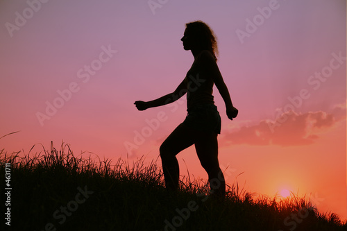 woman rises on a slope of a hill on sunset