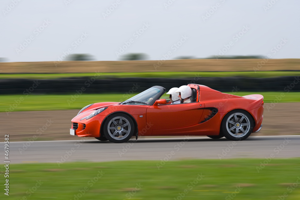 Bright red sports car at speed on a race circuit