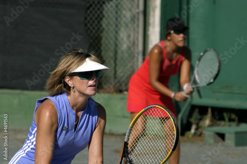middle aged females playing tennis doubles © tracyhornbrook