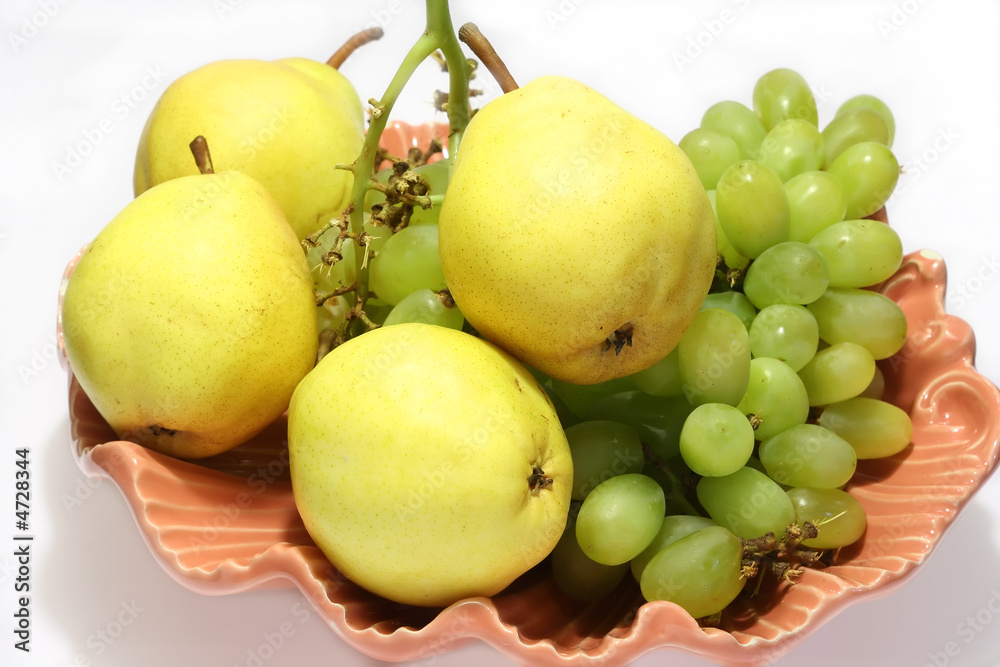 pears and grapes in pink vase with white background