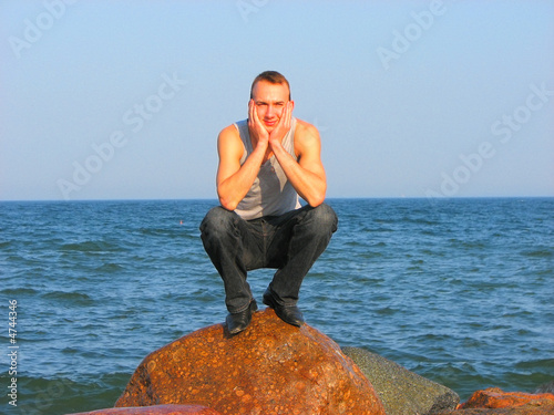 young man sitting on a stone closeup