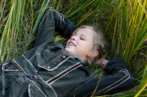 young blond girl lying in the grass