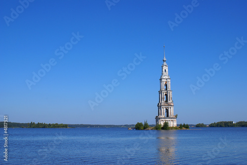 High belltower in the middle of the wide river