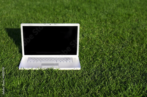 Laptop on field of green grass