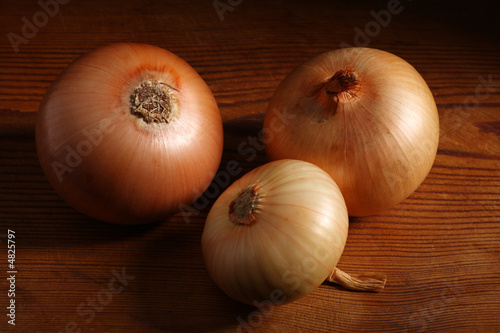 Three onions on old wooden board
