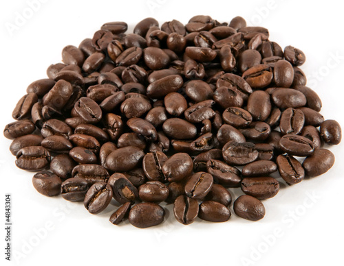 Pile of roasted coffee beans on a white background.