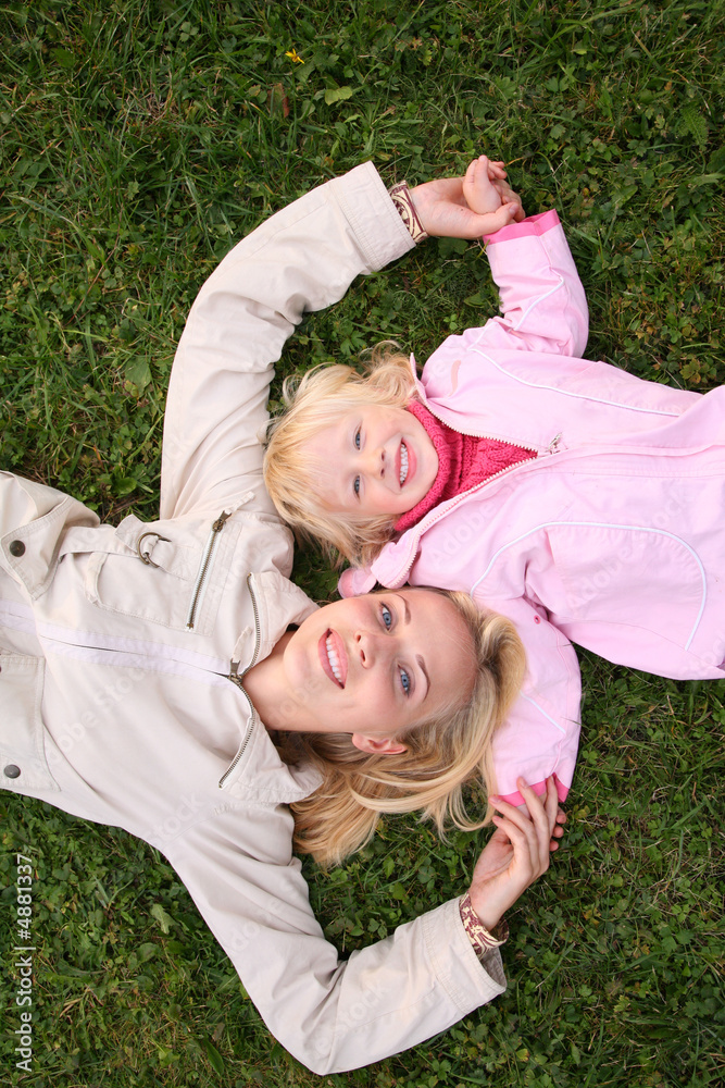 mother and daughter lie on grass mother and daughter lie on grass