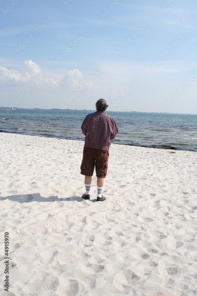 Lonely man standing on the beach in front of the sea , Sweden