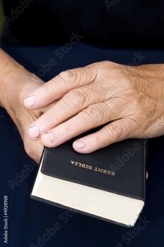 Old hands holding worn Bible
