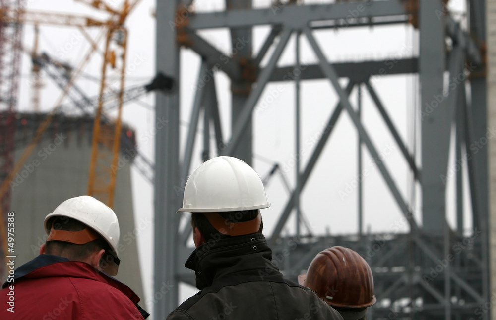 Drei Bauarbeiter mit Helm auf Großbaustelle Drei Bauarbeiter mit Helm auf Großbaustelle
