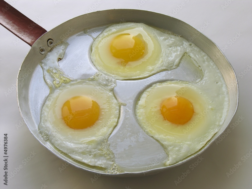 three fried eggs on an old alloy frying pan three fried eggs on an old alloy frying pan
