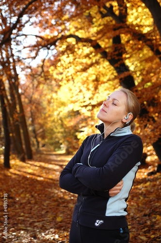 Young, sporty woman listening music in the park