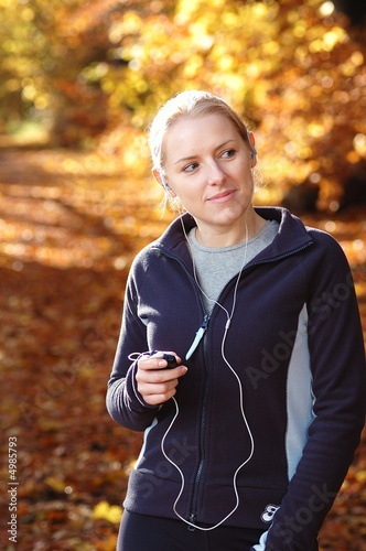 Young, sporty woman listening music in the park