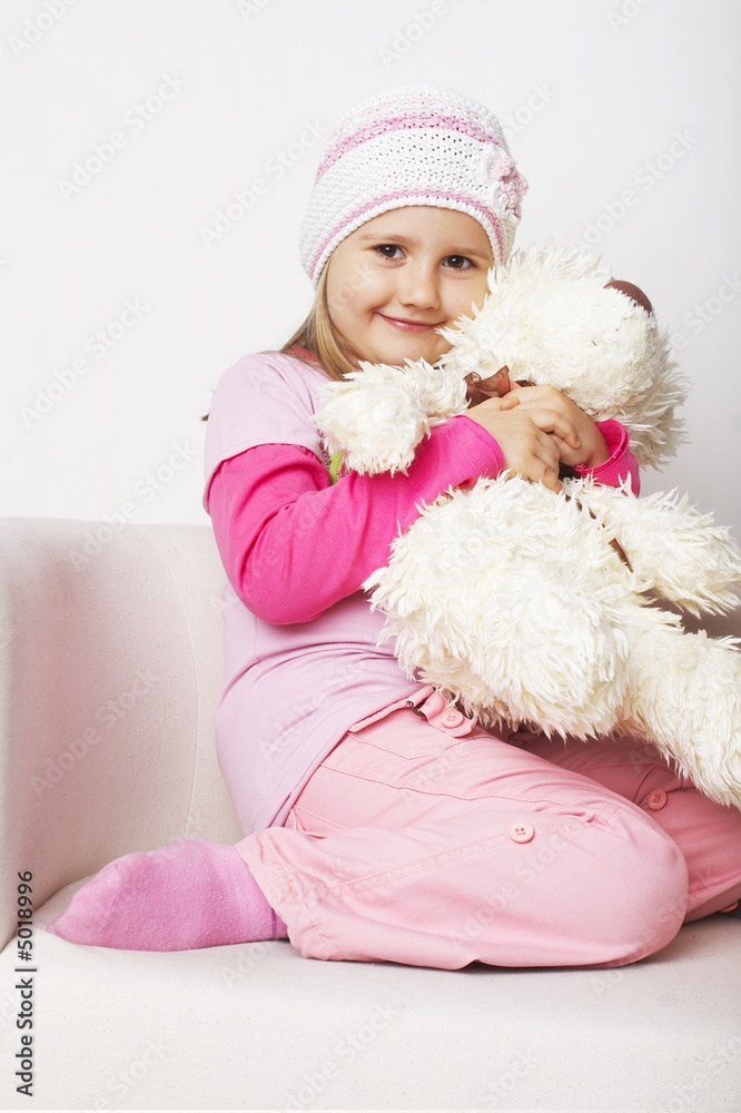 Nice young girl in pink on light background with teddy bear