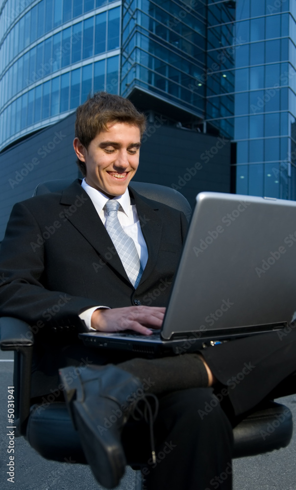 Handsome confident businessman working on his laptop in front of