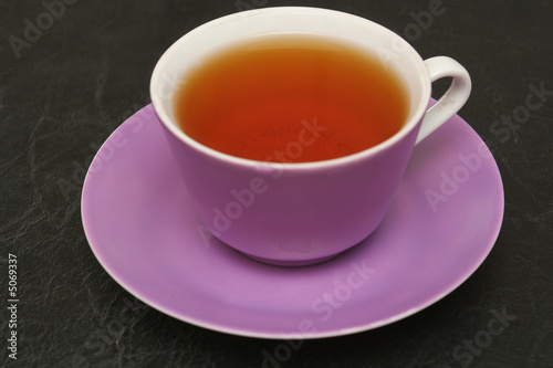 Lilac cup with tea on a black background